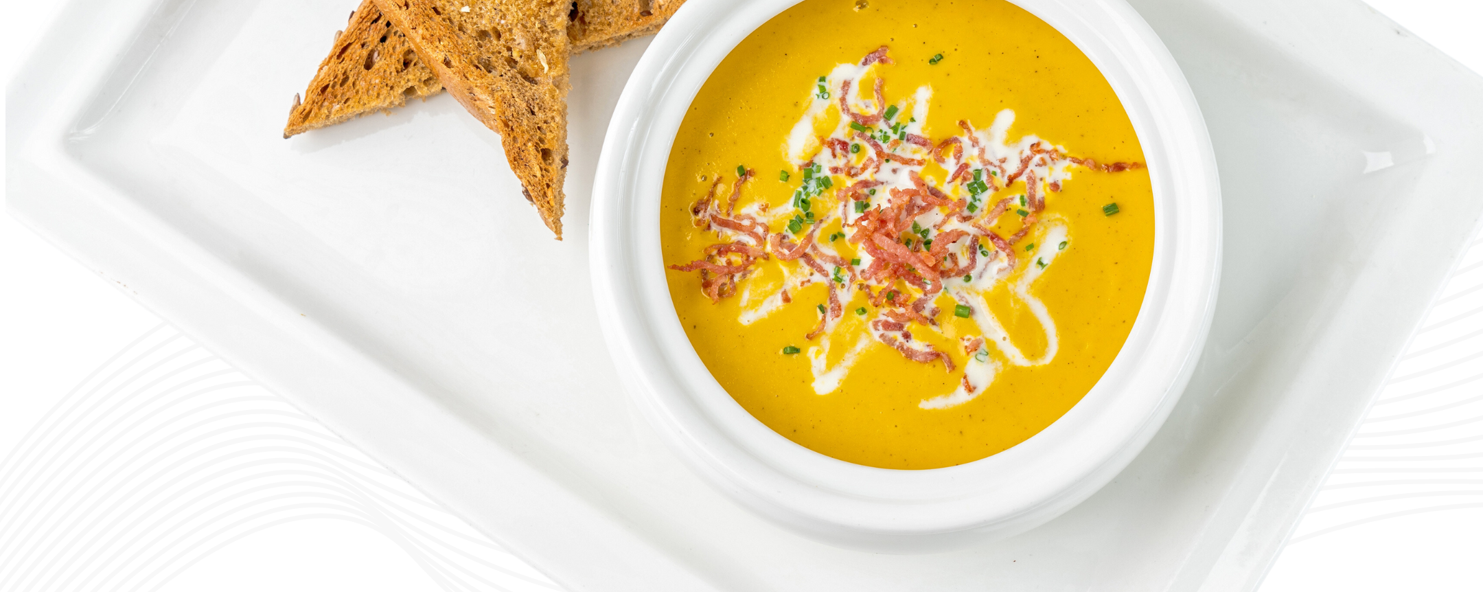 a bowl of rich winter squash soup displayed elegantly in a white bowl with two triangles of wheat bread on the side. Featured on dcnorrisna.com home page.