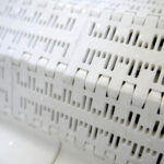 an extreme closeup of the belt on the belt tumble chiller by DC Norris. The belt is smooth plastic with no extruding parts that might compromise the product bags