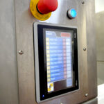 emergency stop and a closeup of the HMI control screen on the DC Norris Belt Tumble Chiller
