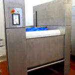 DC Norris North America belt tumble chiller with blue bags loaded onto it