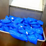 bright blue bags are filled with product waiting to be chilled on the DC Norris North America belt tumble chiller