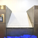 the belt of the DCN belt tumble chiller is raised to dump cooled product into a tote bin
