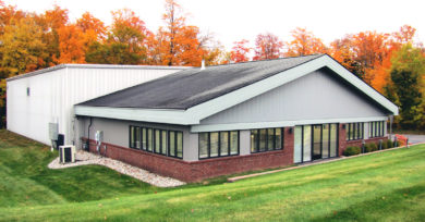 exterior view of the new DC Norris North America office in Traverse City, Michigan. A grey building with large windows and a lower brick accent.